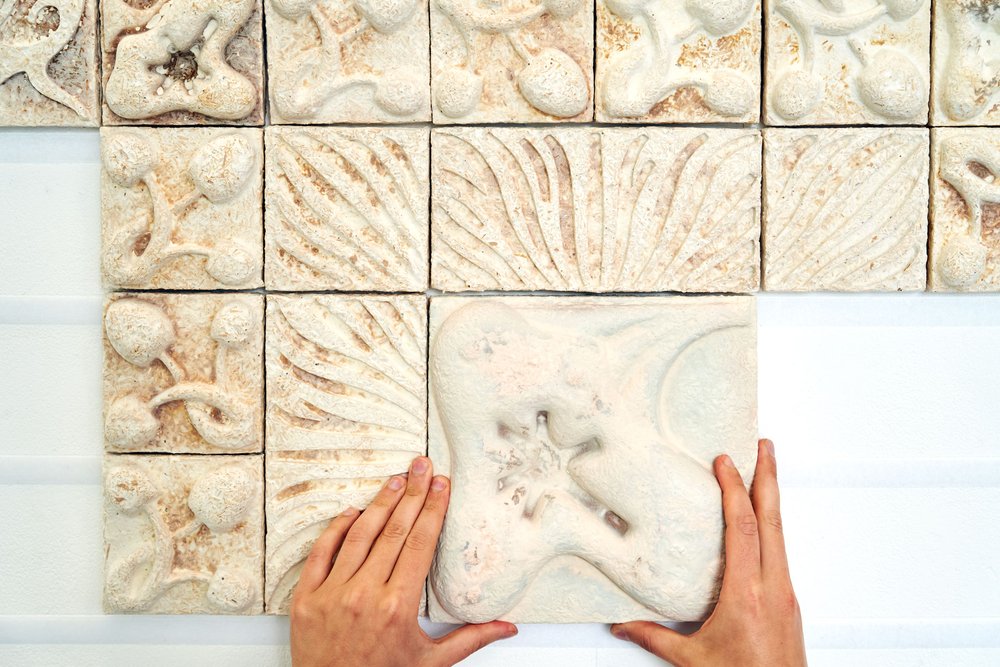 Section of decorative tiles made from mycelium, being mounted on a wall.