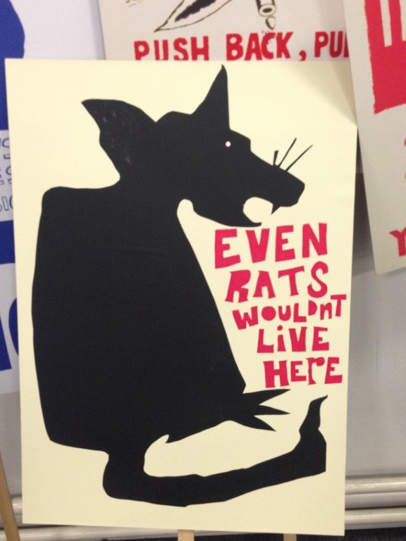 A black rat on a white paper with the red words "Even rats wouldn't live here."