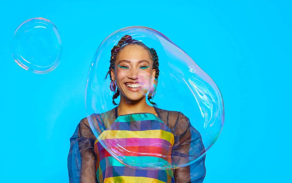 Photograph of a smiling model with a large bubble in front of her, image created for Amazon Launchpad storefront
