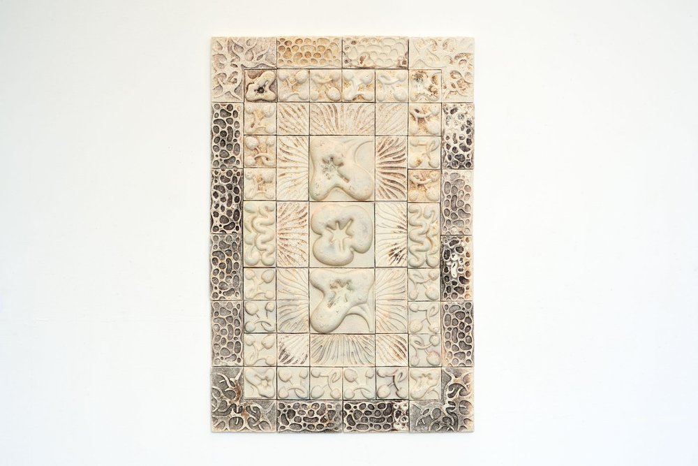 Photograph of decorative tiles made from mycelium, hung on a wall.