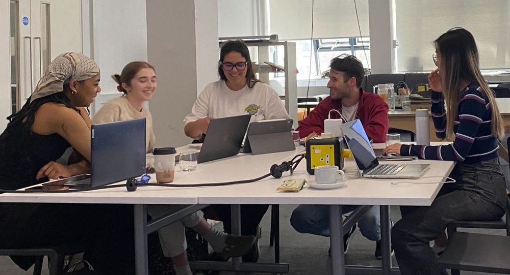 Tom from Nonsense talking with a group of students at a table