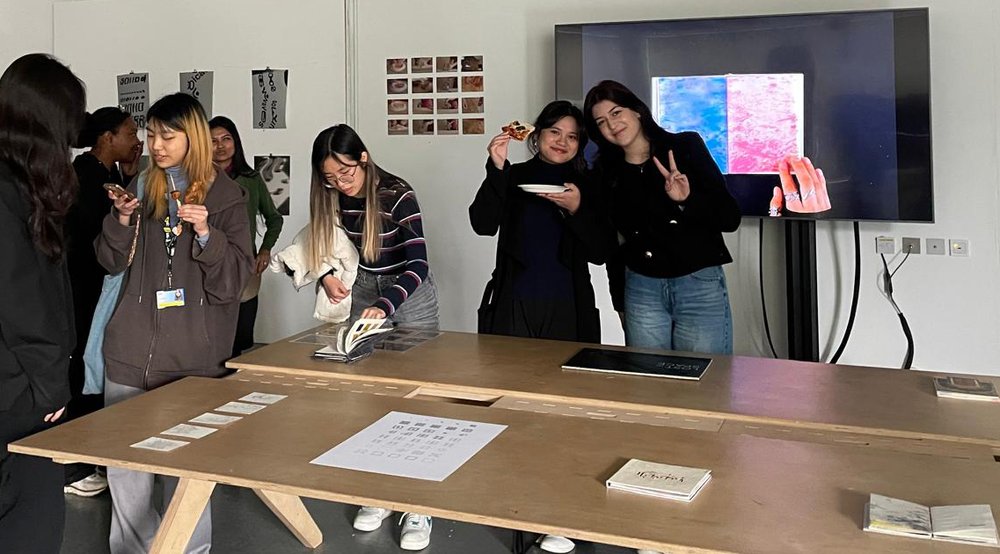 Exhibition view showing students looking at publications on tables.